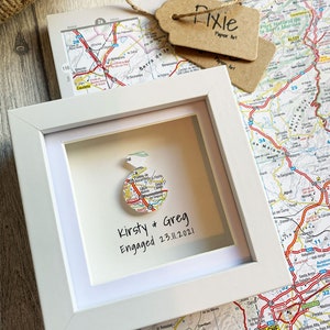 Pu&ograve; includere: Una cornice bianca con una mappa di una citt&agrave; al suo interno. La mappa &egrave; circolare ed &egrave; circondata da un bordo bianco. Il testo "Kirsty & Greg Engaged 23.11.2021" &egrave; scritto sotto la mappa.