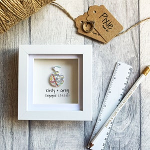 Pu&ograve; includere: Una cornice bianca con una mappa all'interno. La mappa &egrave; un cerchio e ha il testo "Kirsty & Greg Engaged 23.11.2021".