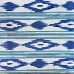 Könnte beinhalten: Weißer Stoff mit einem blauen und grünen Ikat-Muster. Das Muster zeigt eine sich wiederholende Diamantform mit einer weißen Mitte.