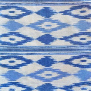 K&ouml;nnte beinhalten: Wei&szlig;er Stoff mit einem blauen und hellblauen geometrischen Muster. Das Muster ist eine sich wiederholende Diamantform mit einer kleineren Diamantform im Inneren.