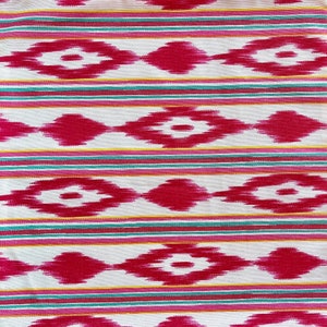 K&ouml;nnte beinhalten: Wei&szlig;er Stoff mit einem sich wiederholenden Muster aus rosa und roten Rauten mit wei&szlig;em Zentrum. Der Stoff hat d&uuml;nne Streifen in Gelb, Rosa und T&uuml;rkis.
