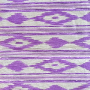 K&ouml;nnte beinhalten: Lilafarbener und wei&szlig;er Stoff mit einem geometrischen Muster. Das Muster ist eine sich wiederholende Diamantform mit einer wei&szlig;en Mitte und lilafarbenen R&auml;ndern.