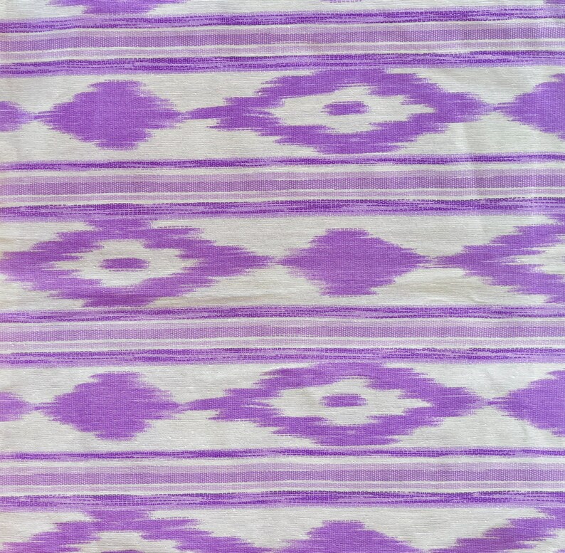 K&ouml;nnte beinhalten: Lilafarbener und wei&szlig;er Stoff mit einem geometrischen Muster. Das Muster ist eine sich wiederholende Diamantform mit einer wei&szlig;en Mitte und lilafarbenen R&auml;ndern.