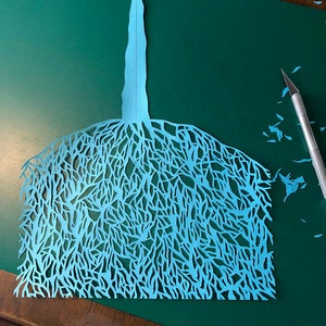 Puede incluir: Un recorte de papel azul de un &aacute;rbol con ramas intrincadas y un solo tronco.
