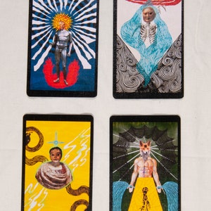 Puede incluir: Cuatro cartas de tarot con bordes negros e ilustraciones coloridas. La primera carta tiene un fondo azul con un sol blanco y una figura plateada de pie sobre una llama roja. La segunda carta tiene un fondo blanco y negro con una figura azul con un esqueleto en su interior. La tercera carta tiene un fondo amarillo con una figura blanca y negra con una cruz encima. La cuarta carta tiene un fondo verde con una figura blanca y negra con cabeza de zorro y agua azul que fluye de sus manos.