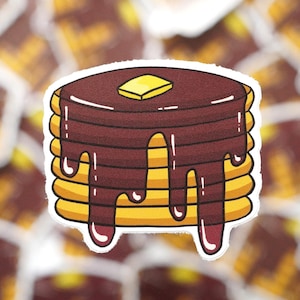May include: A stack of six yellow pancakes topped with brown chocolate syrup and a small yellow square of butter.