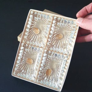 May include: Set of four clear glass square dishes with a decorative cut-glass pattern. The dishes are arranged in a square shape and are displayed in a white box.