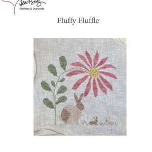 May include: Cross stitch pattern featuring a pink flower, a brown rabbit, and two smaller rabbits. The pattern is titled "Fluffy Fluffle" and has the number 00027.