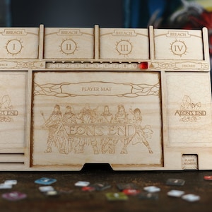 May include: A wooden board game organiser for Aeon's End. The organiser has slots for cards labelled "Breach" and "Deck", a player mat area with the text "Player Mat" and "Aeon's End", and a player number slot. The design is etched into the wood.