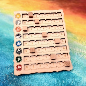 May include: A wooden game board with etched lines and numbers from 0 to 6. Small wooden cubes are placed on the board. The board has colorful symbols along the left side. The background is a mix of blue, yellow, and orange.