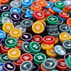 Può includere: Una collezione di gettoni rotondi e colorati con vari simboli e disegni. I gettoni sono in plastica e hanno una finitura lucida.