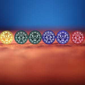 Könnte beinhalten: Acht farbige, runde Spielmarken mit einem Trophäen-Design. Die Spielmarken sind in Gelb, Grün, Blau und Rot gehalten und haben weiße Umrisse. Der Hintergrund ist ein Farbverlauf von Orange und Blau.