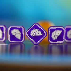 May include: Five purple game tokens featuring a white nautilus shell design. The central token is diamond-shaped, the others are square. The tokens are set against a blurred blue and orange background, creating a vibrant contrast.
