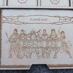 May include: A wooden player mat for the board game Aeon's End. The mat features a light brown background with a dark brown border and a stylized image of five characters from the game. The text "PLAYER MAT" and "AEON'S END" are printed on the mat.