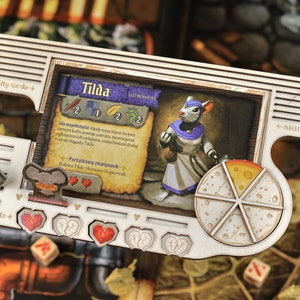 Könnte beinhalten: Ein hölzernes Spielbrettstück für ein Brettspiel mit einer Comic-Mausfigur namens Tilda. Das Stück hat eine Charakterkarte, ein Käse-Rad und einen Herz-Gesundheits-Tracker. Die Charakterkarte zeigt ein Bild von Tilda, eine Beschreibung ihrer Fähigkeiten und eine Liste ihrer Ausrüstung. Das Käse-Rad hat sechs Käsescheiben und der Herz-Gesundheits-Tracker hat fünf Herzen.