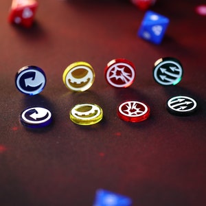 May include: A set of nine colorful round tokens with different white symbols on them. The tokens are made of glass and have a glossy finish. The symbols include a circle with an arrow, a gear, a starburst, and three arrows.