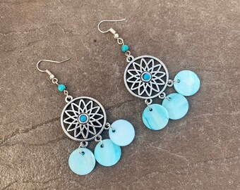 Pode incluir: Brincos de prata com um design de flor azul turquesa e detalhes de concha azul e branca.