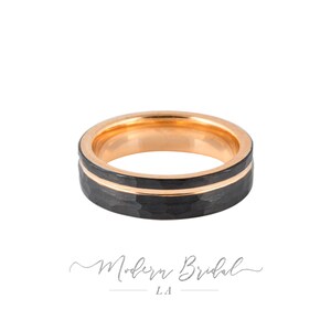 Peut inclure: Une bague en carbure de tungstène noir avec un incrustation en or rose. La bague a une finition martelée.