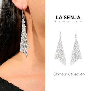 May include: Silver dangle earrings with a chain link design. The earrings are part of the Glamour Collection by La Senja Jewelry.