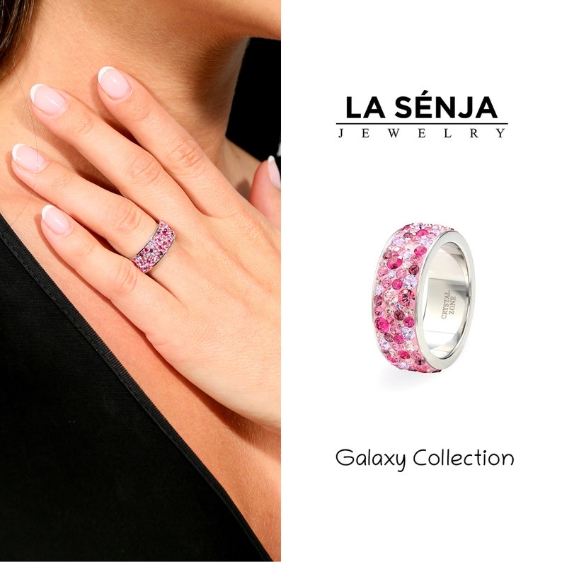 May include: A silver ring with a band of pink and purple crystals. The ring is part of the Galaxy Collection by La Senja Jewelry.
