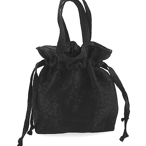 Può includere: Borsa nera in velluto con coulisse e motivo floreale. Ha due manici e cordini per la chiusura. Il tessuto è morbido e strutturato.