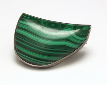 May include: A silver brooch with a green malachite stone in the shape of a crescent moon.
