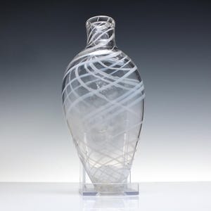 May include: A clear glass bottle with white swirling lines. The bottle has a rounded bottom and a narrow neck.