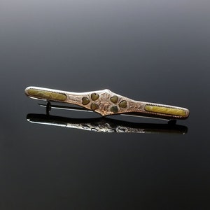 Könnte beinhalten: Eine silberne Brosche mit einem grünen Stein-Design. Der Stein ist in Herzform gefasst und von einem silbernen Rahmen umgeben. Die Brosche ist etwa 5 cm lang.