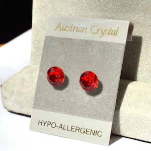 May include: A pair of red Austrian crystal stud earrings on a white card with the text "Austrian Crystal" and "Hypo-allergenic".