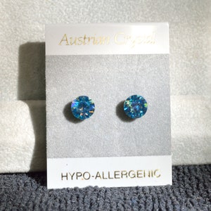 May include: A pair of blue crystal stud earrings on a white card with the text "Austrian Crystal" and "Hypo-allergenic".