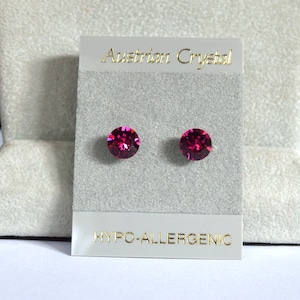 May include: A pair of small, round, pink crystal earrings on a gray card with the text "Austrian Crystal" and "Hypo-allergenic".