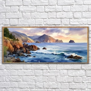 K&ouml;nnte beinhalten: Gerahmtes Aquarellgem&auml;lde einer K&uuml;stenlandschaft. Das Kunstwerk zeigt eine felsige K&uuml;stenlinie mit brechenden Wellen, Bergen im Hintergrund und einen farbenfrohen Sonnenuntergang. Das Gem&auml;lde befindet sich in einem Holzrahmen und ist an einer wei&szlig;en Backsteinmauer befestigt.