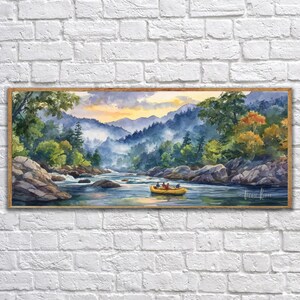 May include: Watercolor painting of a river scene with a yellow raft carrying people. The landscape features mountains, trees, and rocks, with a warm, colorful sky. The artwork is framed in a wooden border.