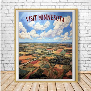 May include: A framed vintage travel poster with the text "VISIT MINNESOTA" in red. The artwork shows a colourful aerial view of farmland under a blue sky with fluffy white clouds. The poster is in a gold frame.