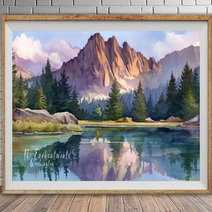 May include: Watercolor landscape art print featuring a mountain range reflected in a lake. The artwork showcases a serene scene with lush green trees, rocky shores, and a sky with soft clouds. The frame is a warm, natural wood.