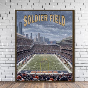Puede incluir: Un póster enmarcado que representa el Soldier Field en Chicago, Illinois, durante un partido de fútbol americano bajo la nieve. La imagen muestra el estadio lleno de espectadores, el campo verde con postes de meta y el horizonte de la ciudad.