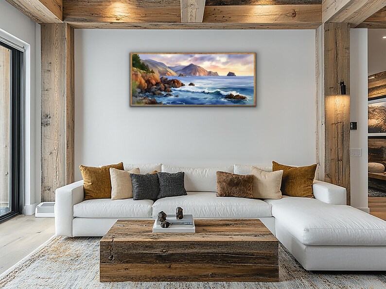 K&ouml;nnte beinhalten: Ein gerahmtes Landschaftsgem&auml;lde zeigt eine K&uuml;stenlandschaft mit felsigen Klippen, tosenden Wellen und einem ruhigen Ozean unter einem Sonnenuntergangshimmel. Das Kunstwerk weist warme T&ouml;ne von Orange, Blau und Gold auf.