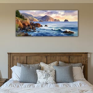 K&ouml;nnte beinhalten: Ein Landschaftsgem&auml;lde einer K&uuml;stenlandschaft. Das Kunstwerk zeigt eine felsige K&uuml;stenlinie mit Wellen, die gegen die Felsen schlagen. Berge sind im Hintergrund unter einem Sonnenuntergangshimmel. Das Gem&auml;lde h&auml;ngt &uuml;ber einem h&ouml;lzernen Bettrahmen.