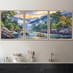 May include: A triptych of framed watercolor paintings depicting a river scene. The artwork features a yellow raft with people, surrounded by lush green trees, rocky shores, and misty blue mountains under a sunset sky.
