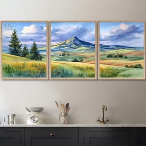 Peut inclure: Un triptyque de peintures de paysage à l'aquarelle encadrées. Chaque cadre présente une scène sereine de collines, de champs et d'une montagne sous un ciel nuageux. L'œuvre utilise des verts, des jaunes, des bleus et des bruns, avec le texte "The Painted Adventure" en haut à gauche.