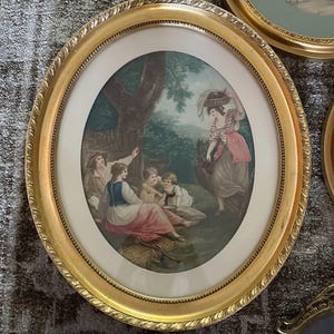 May include: A vintage oval framed print of a woman carrying a basket and four children sitting under a tree. The print is in a gold frame with a white mat.