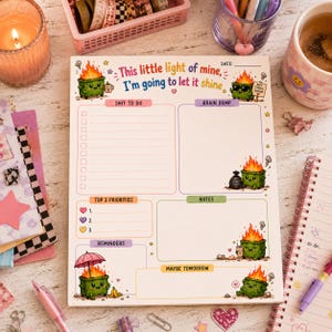 May include: A daily planner notepad featuring the text This little light of mine, I'm going to let it shine. The page includes sections for Shit to do, Brain dump, Top 3 priorities, Notes, Reminders, and Maybe tomorrow, decorated with green dumpster fire illustrations.