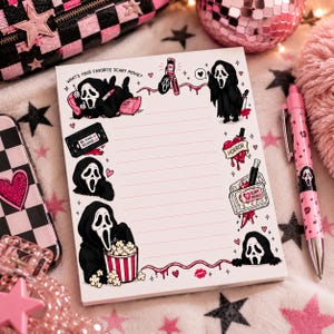 May include: A white lined notepad featuring illustrations of a masked figure in a black robe, a flip phone, a VHS tape labeled BE KIND REWIND, a heart with a knife, and popcorn. The text reads WHAT'S YOUR FAVORITE SCARY MOVIE and SCARY MOVIES.