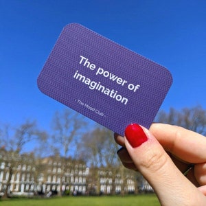 Peut inclure: Carte violette avec un motif en chevron blanc et le texte "The power of imagination - The Mood Club -" en blanc.