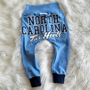 May include: Blue sweatpants with the text "North Carolina Tar Heels" in white on the back.