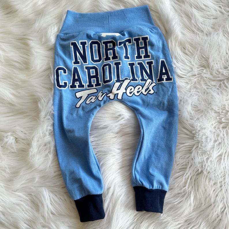 May include: Blue sweatpants with the text "North Carolina Tar Heels" in white on the back.