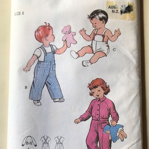 May include: Butterick sewing pattern for children's clothing, featuring illustrations of a toddler in blue plaid overalls, a baby in a diaper, and a girl in a pink jumpsuit. The pattern includes size 6 and the number 476.