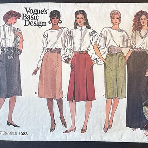 Puede incluir: Patrón de costura vintage Vogue's Basic Design 1023 con ilustraciones de faldas y blusas para mujer. El patrón incluye varios estilos de faldas combinados con diferentes diseños de blusas. Se ven carretes de hilo en la esquina inferior derecha.