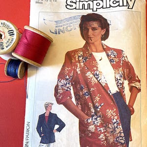 Puede incluir: Un patrón de costura Simplicity vintage con un diseño de blazer floral. El patrón incluye tallas 10, 12 y 14. Se ven carretes de hilo rojo, azul y blanco. El número de patrón es 7286.