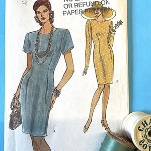 Könnte beinhalten: Vintage Very Easy Very Vogue Schnittmuster 8245 für Kleider, Größen 12-14-16. Die Illustration zeigt zwei Kleiderdesigns, eines in Blau und das andere in Gelb mit weißen Punkten. Garnrollen befinden sich im Vordergrund.